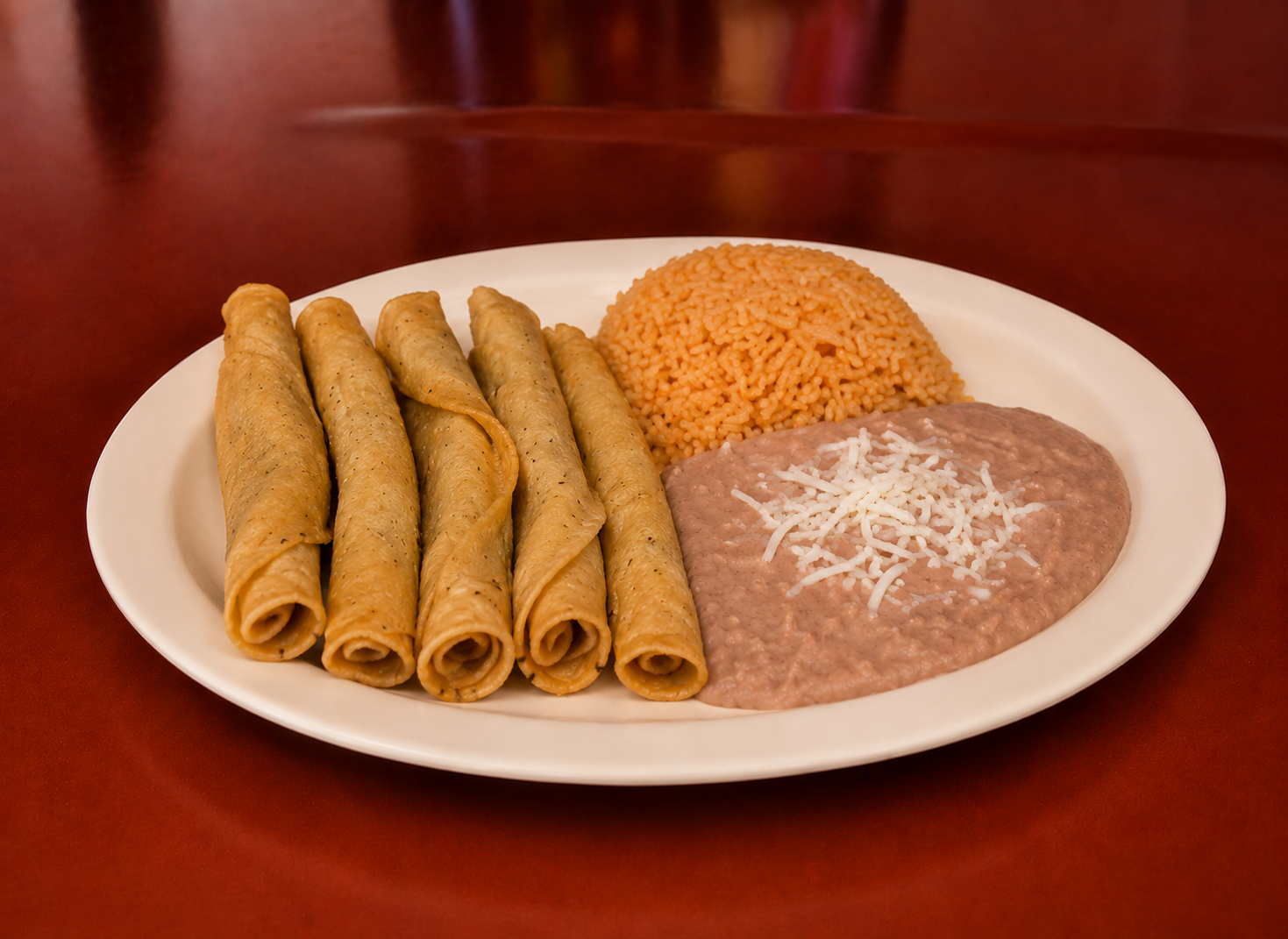 Five crispy flautas with Mexican rice and refried beans topped with queso fresco
