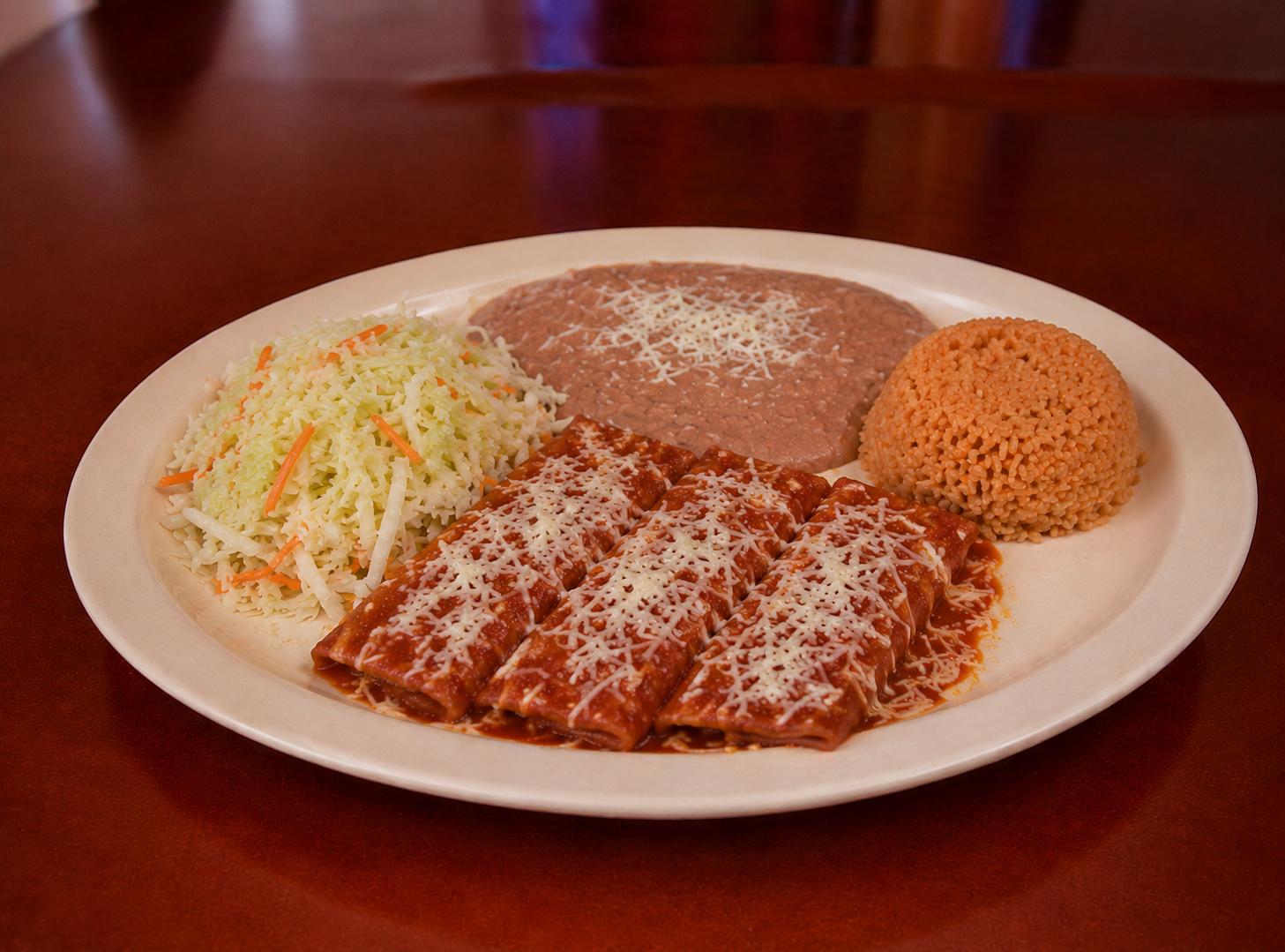 Enchiladas with red sauce, cheese, rice, beans and slaw